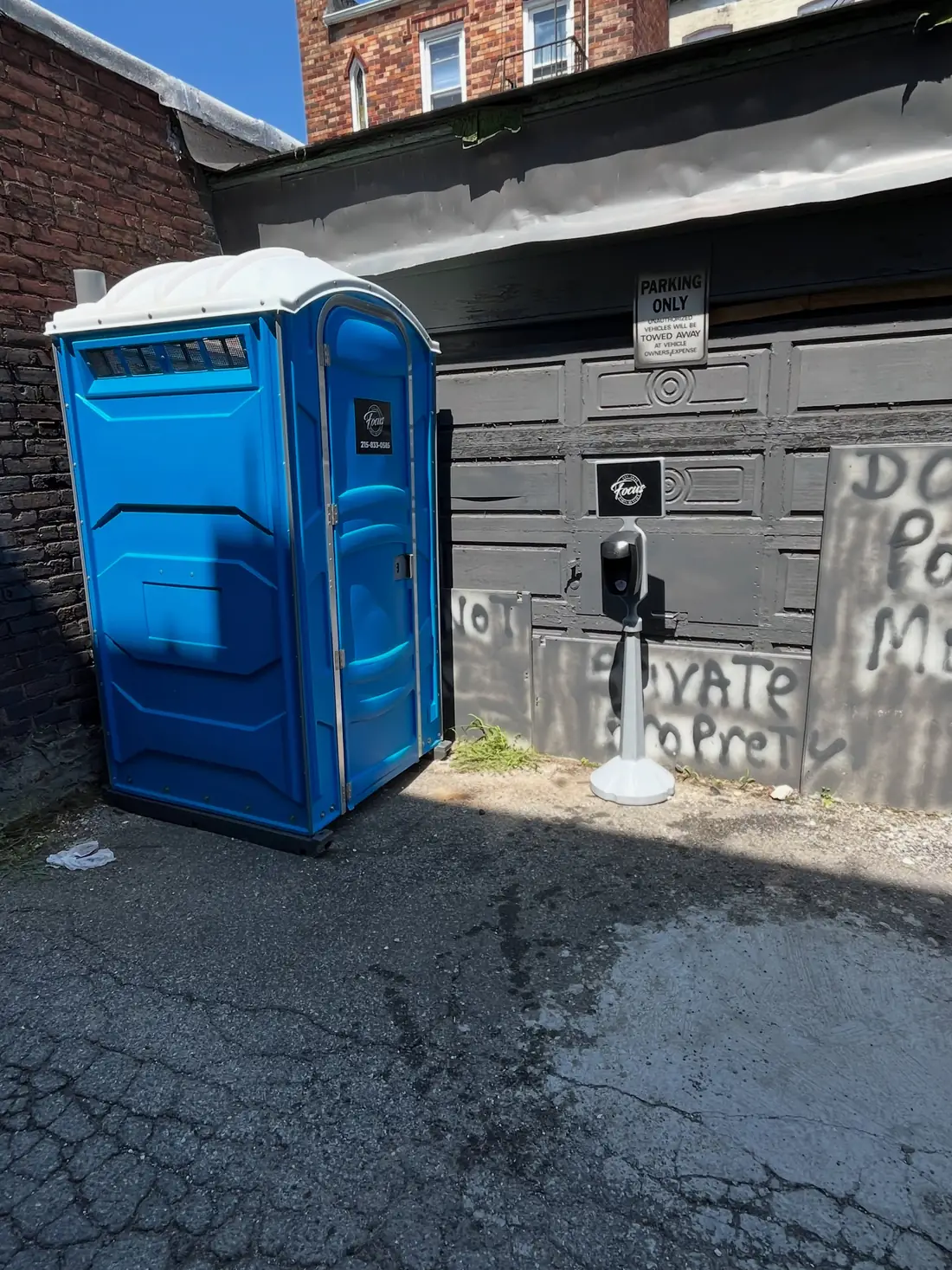 blue porta potty in alley driveway