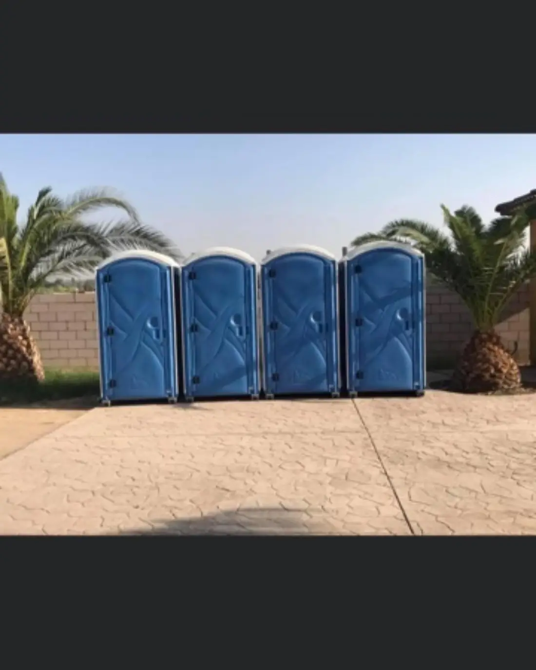 Four portable toilets in a row on concrete