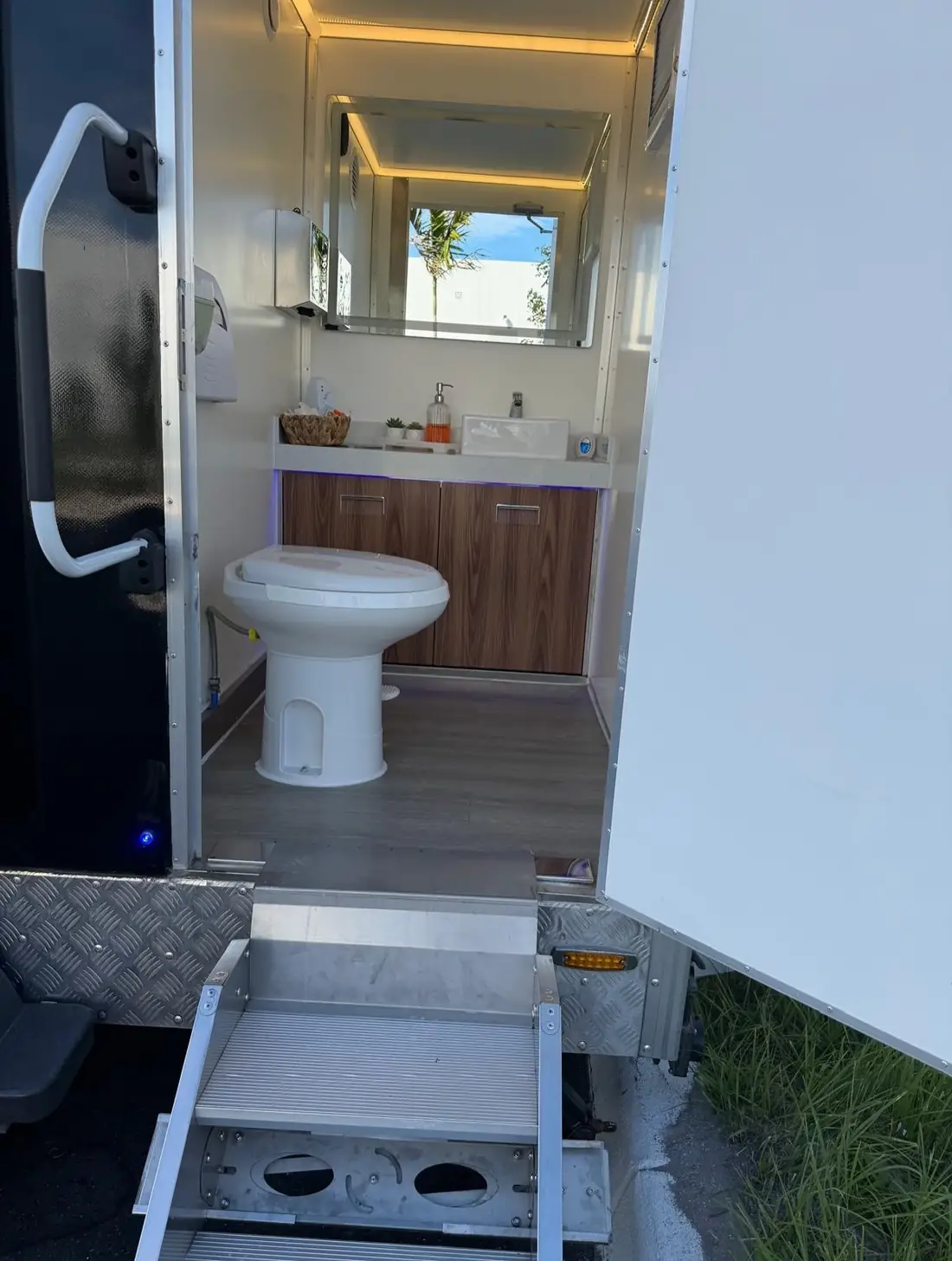 Restroom trailer interior with wood vanity and mirror