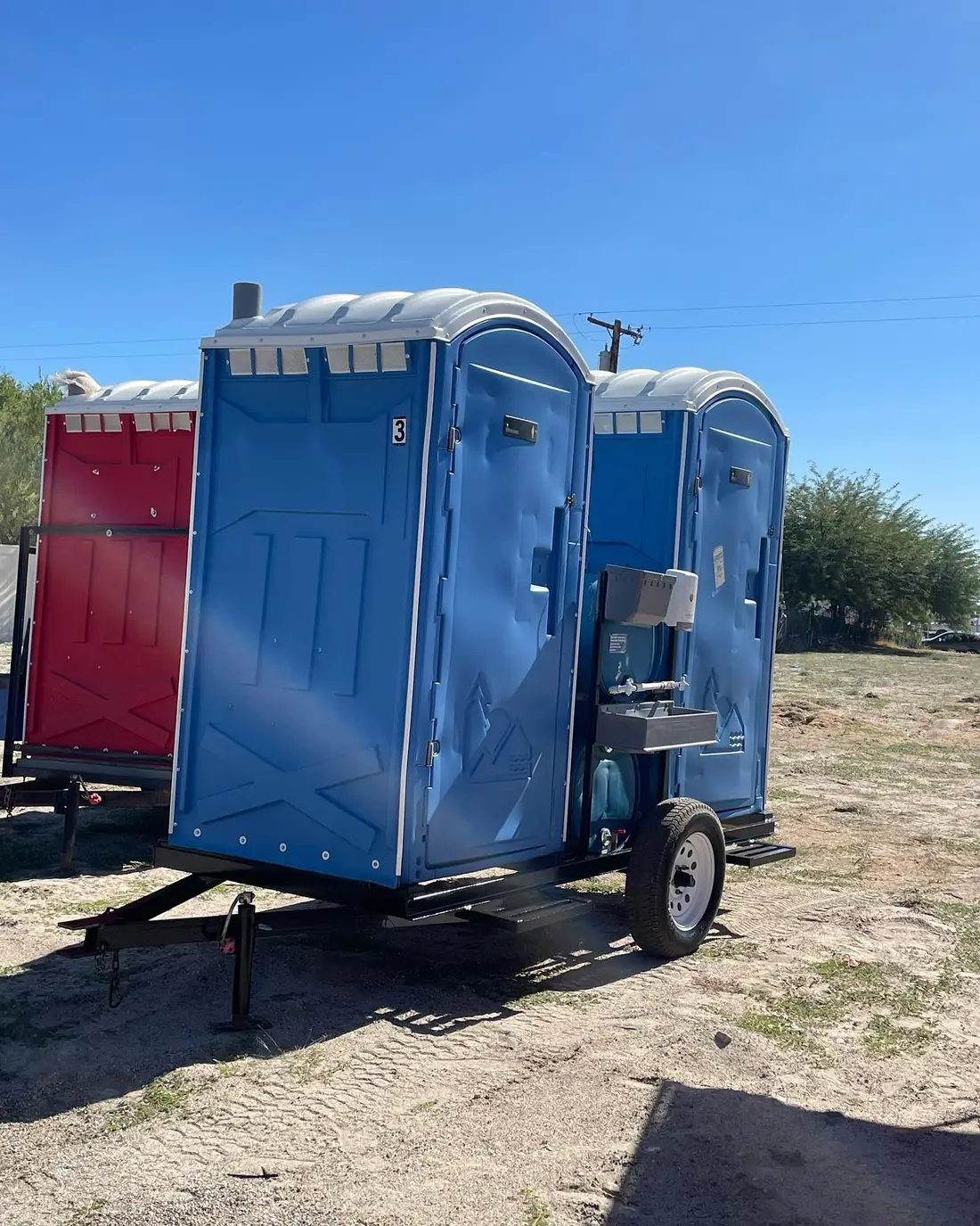 Towable trailer with portable toilets and a sink attached