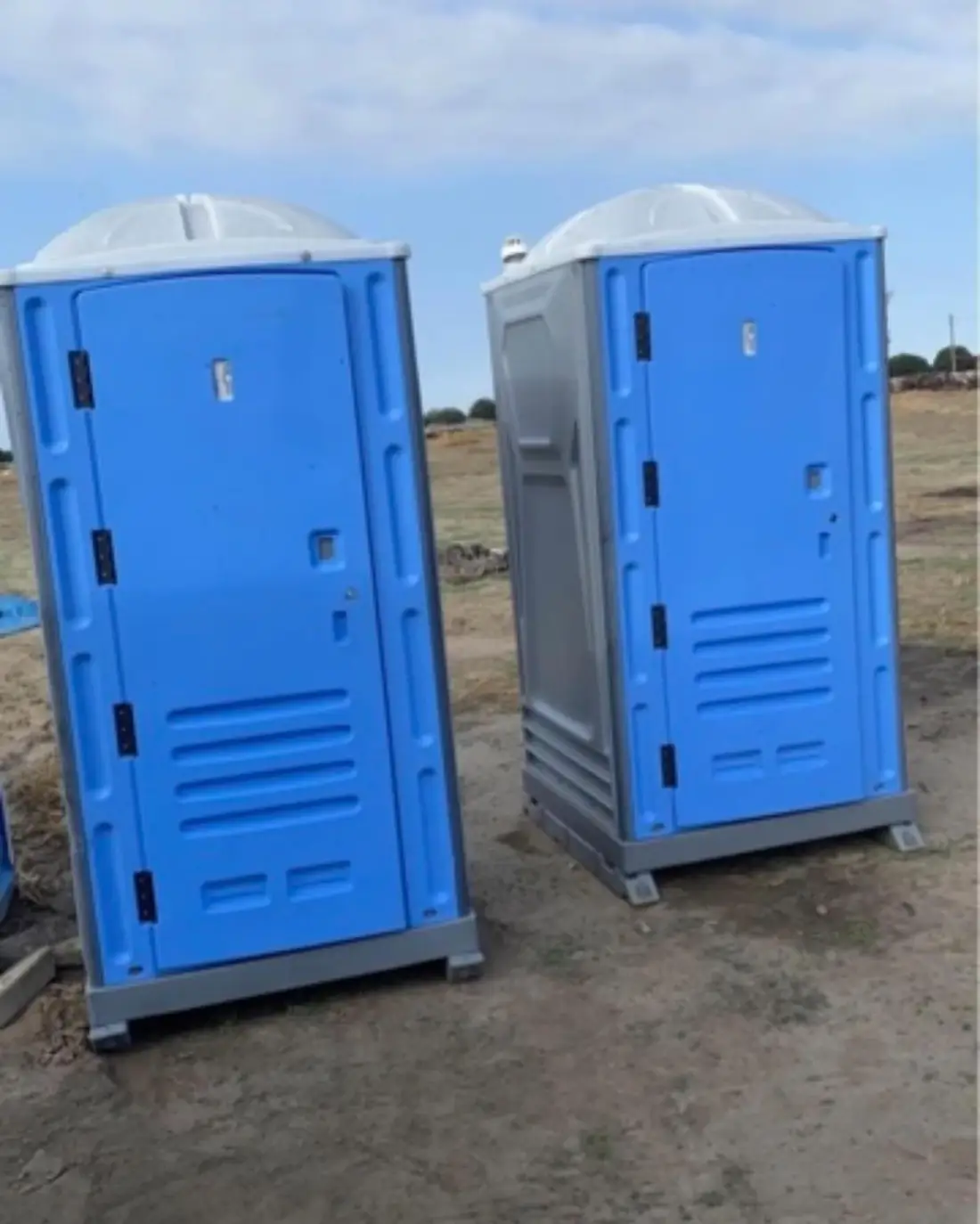 two standard porta potties on open lot
