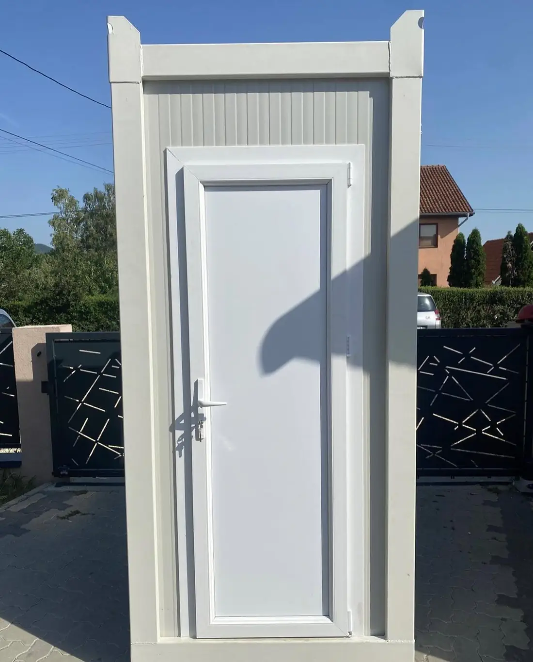 Front view of a white restroom cabin with a residential-style door